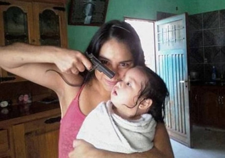 Foto de mulher apontando arma na cabeça de criança gera pânico